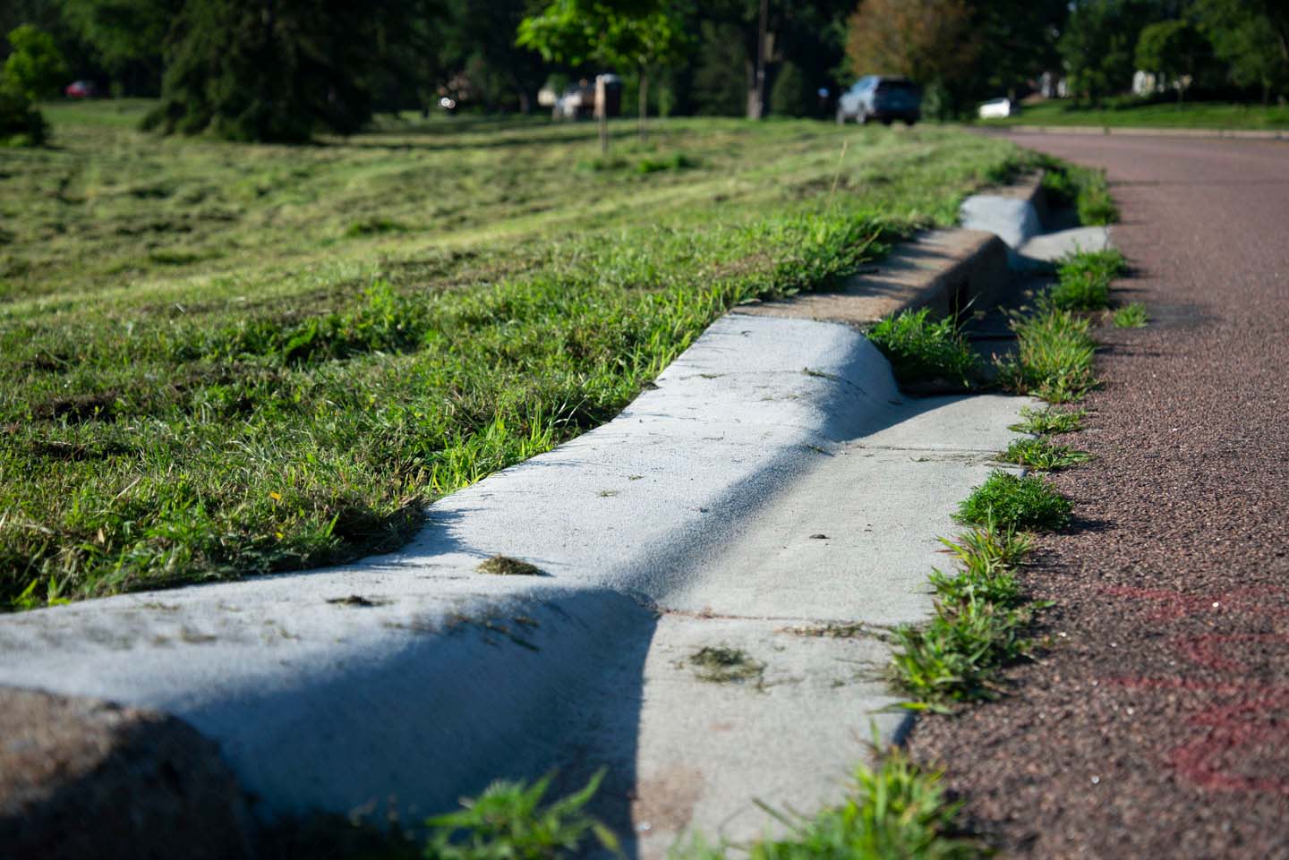 A curb separating the road from a grassy area that is lowered in one section